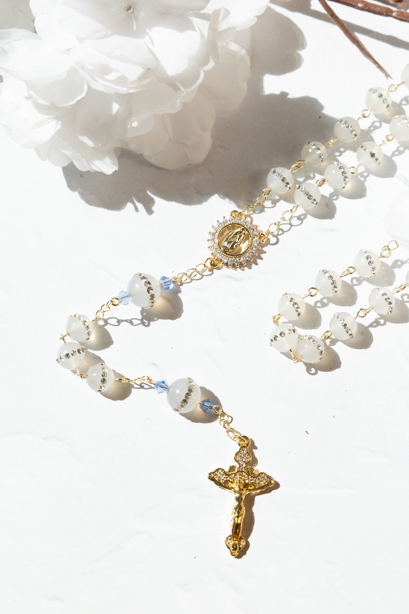 Elegant white and gold rosary with translucent beads, a detailed crucifix pendant, and an ornate central medallion.
