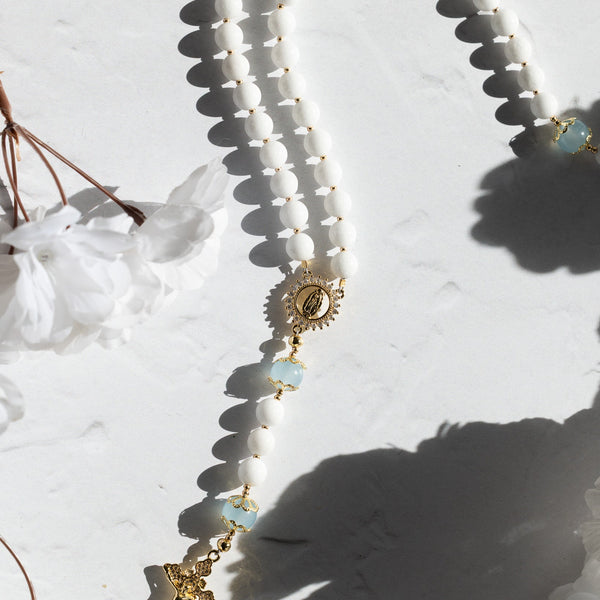 White beaded rosary with gold accents and cross pendant for faithful prayer
