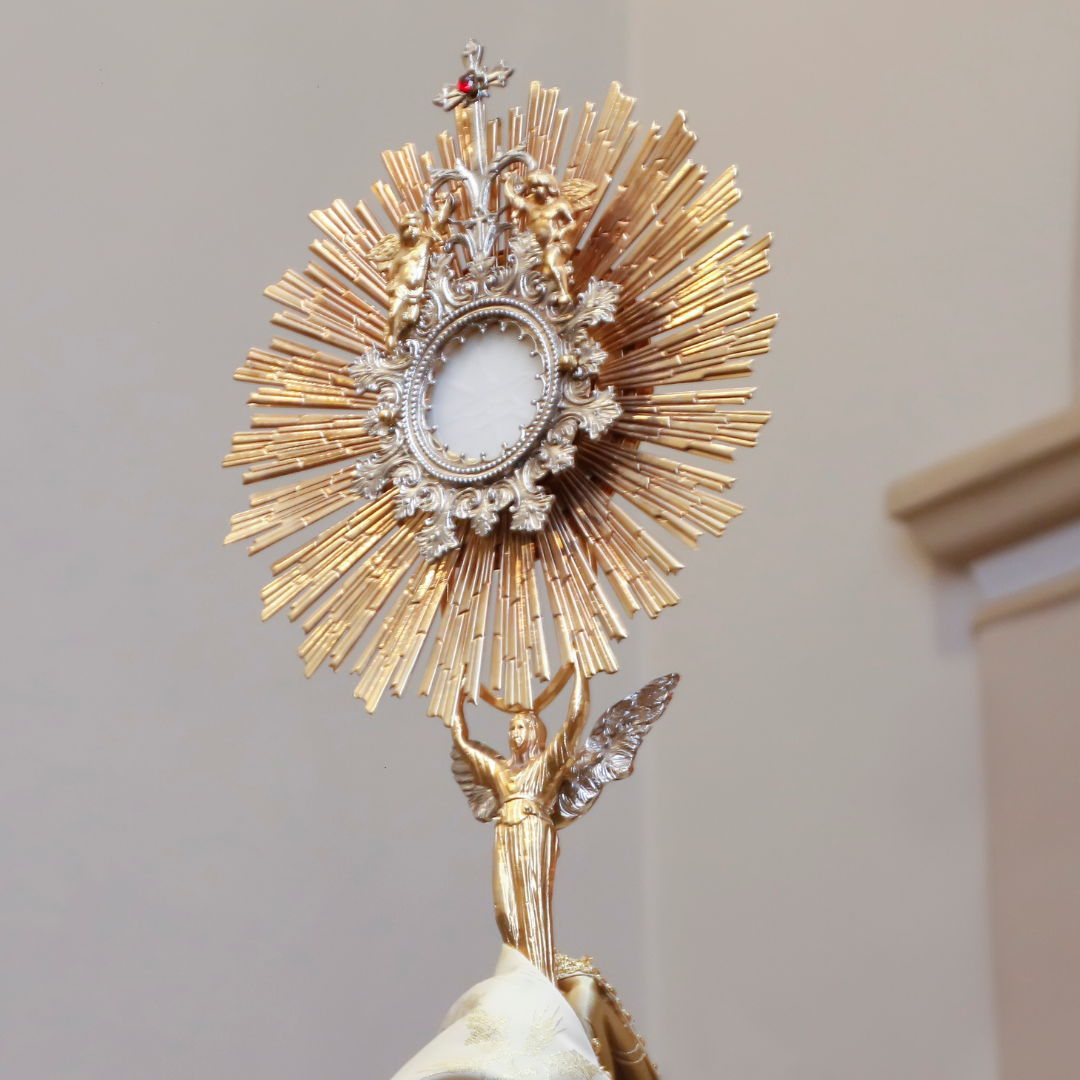 Golden monstrance with sunburst rays and angel figure for Catholic faith growth