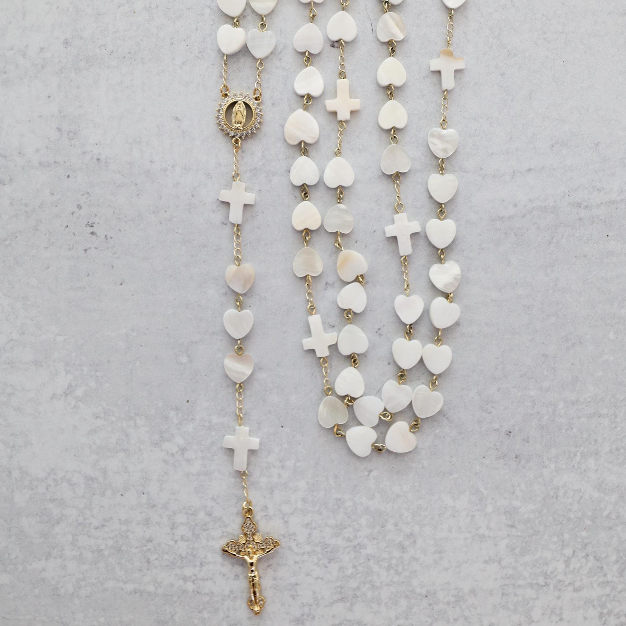 Her Heart Shines pearl heart shaped rosary with gold accents and crucifix on a gray background.