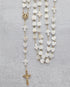 Her Heart Shines pearl heart shaped rosary with gold accents and crucifix on a gray background.