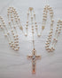 Freshwater pearl wedding lasso rosary with gold findings and a decorative cross pendant on a marble surface.
