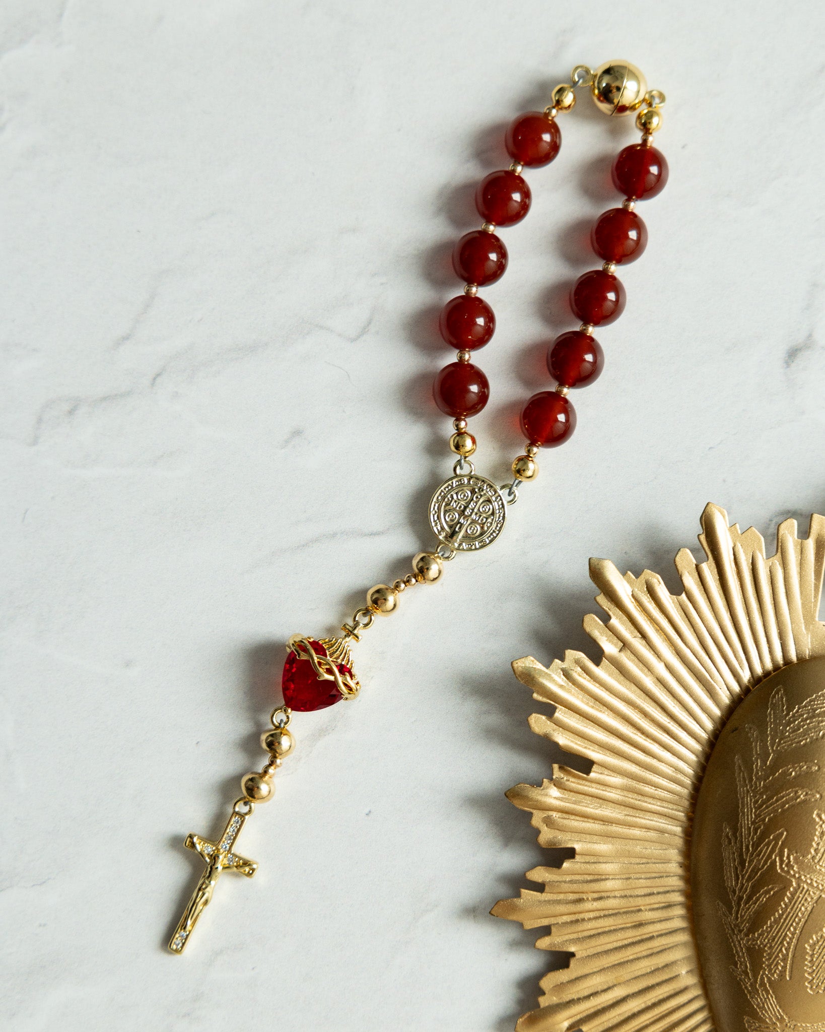 A red and gold rosary with a heart-shaped bead, featuring polished agate beads and metallic accents.