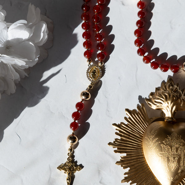 Red beaded rosary with gold-toned metal accents and a detailed crucifix.