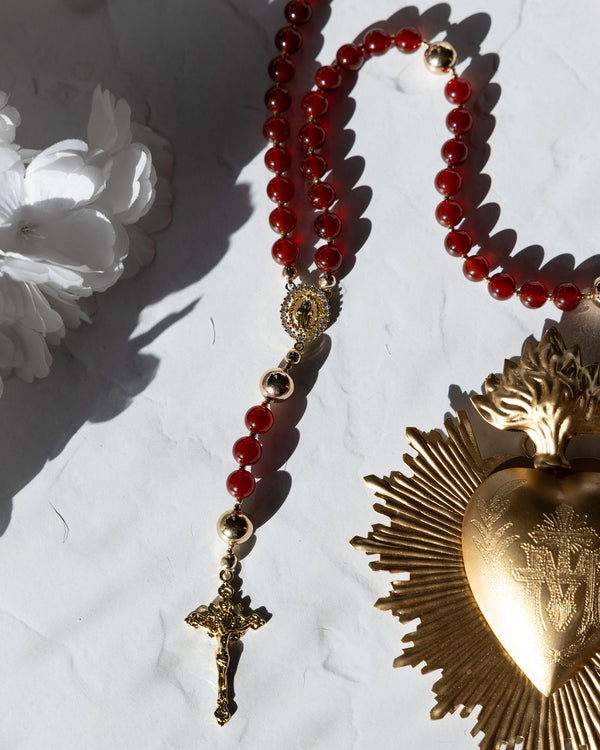 Red beaded rosary with gold-toned metal accents and a detailed crucifix.