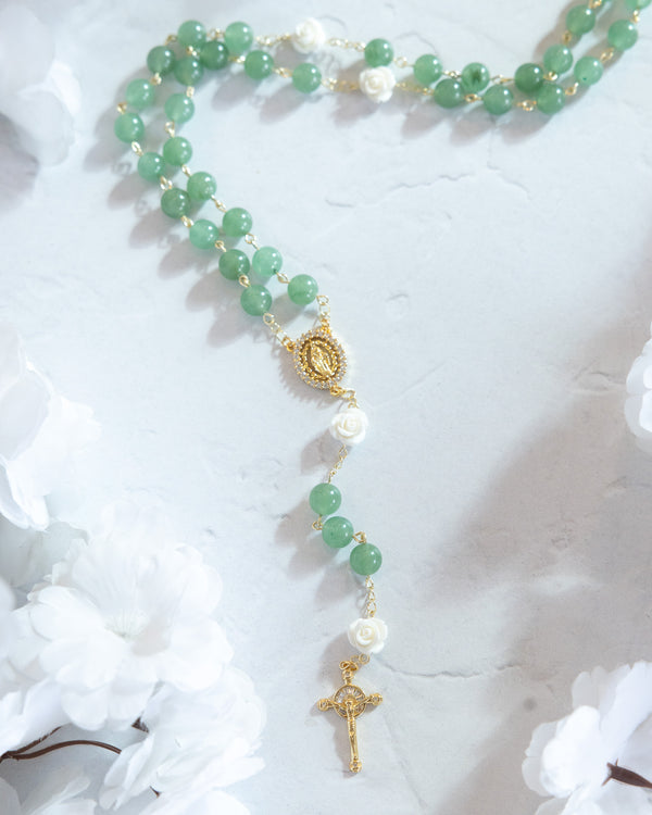 A delicate green jade rosary with gold-toned accents, white rose beads, and a detailed golden crucifix.