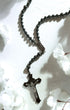 Black rosary with crucifix on a white floral background