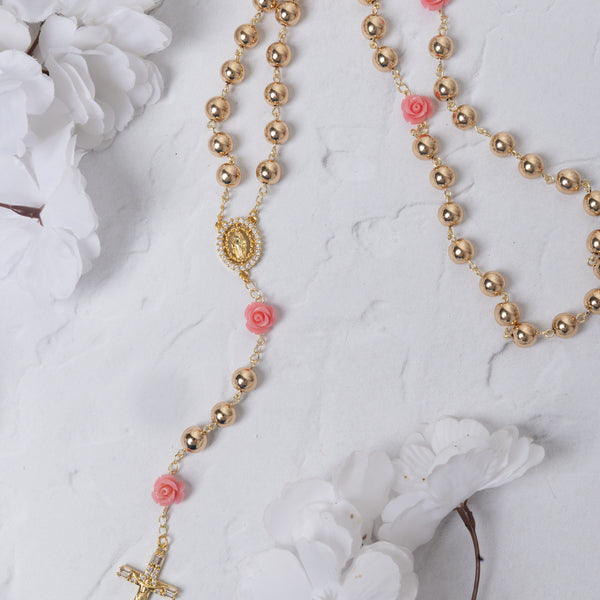 Gold-toned rosary with pink floral accents and a detailed crucifix.