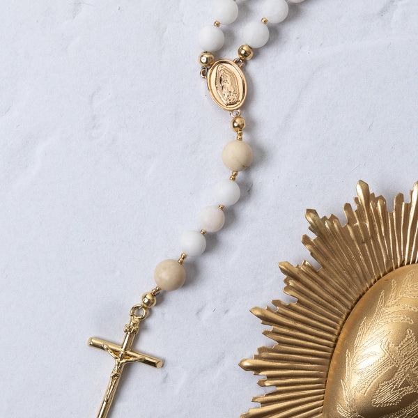 White beaded rosary with gold-toned metal accents and a crucifix.