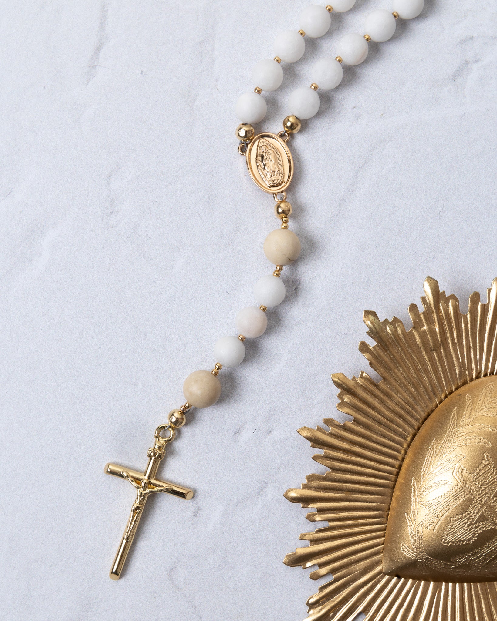 White beaded rosary with gold-toned metal accents and a crucifix.