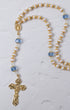 Elegant gold-toned rosary featuring alternating white pearls and faceted blue crystals, with an ornate crucifix pendant.