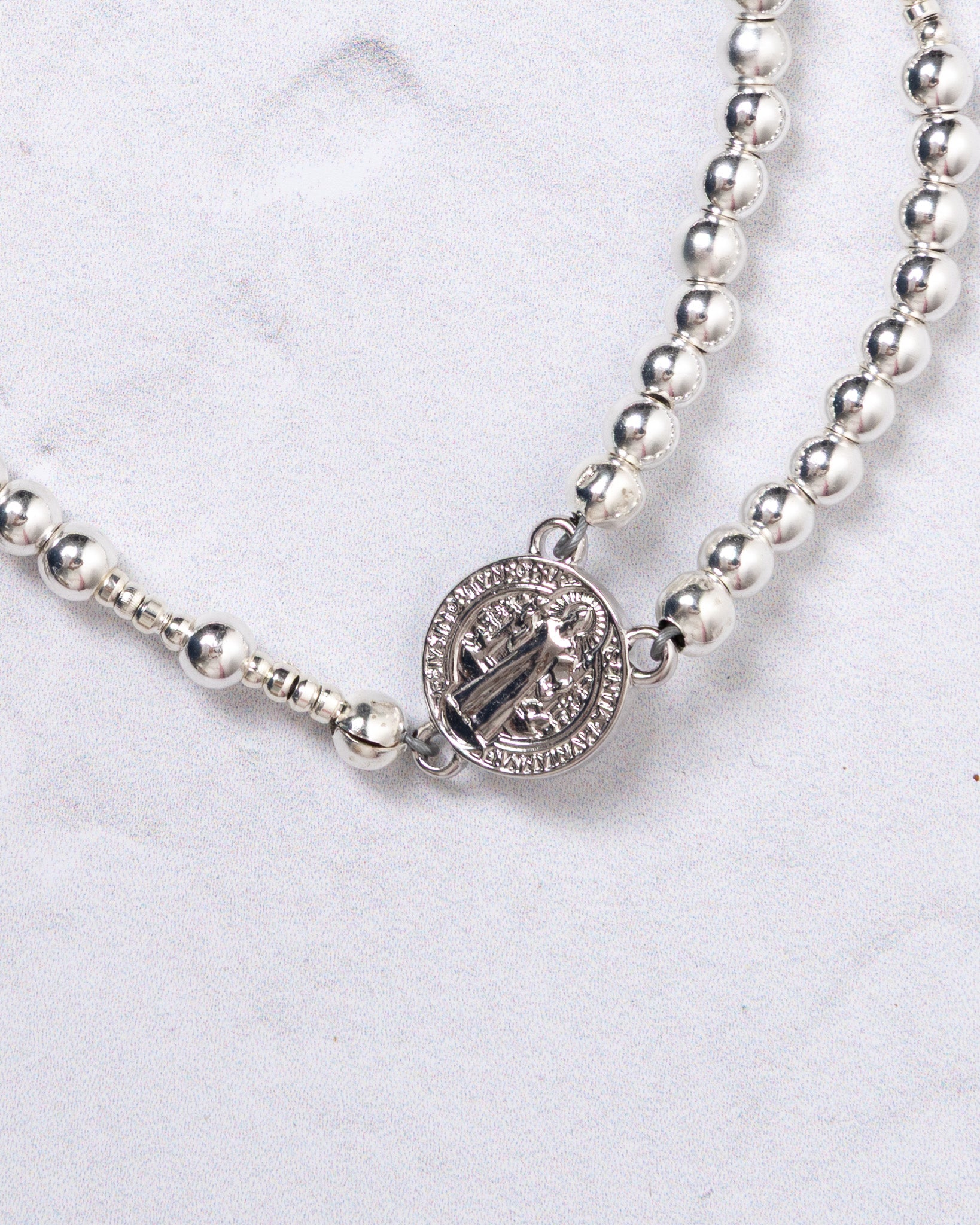 Silver beaded necklace with Saint Benedict medal on white gold magnetic rosary bracelet