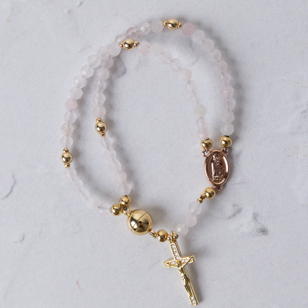 Rose quartz magnetic rosary bracelet with delicate double strands, translucent pink beads, gold-toned accents, and oval medallion
