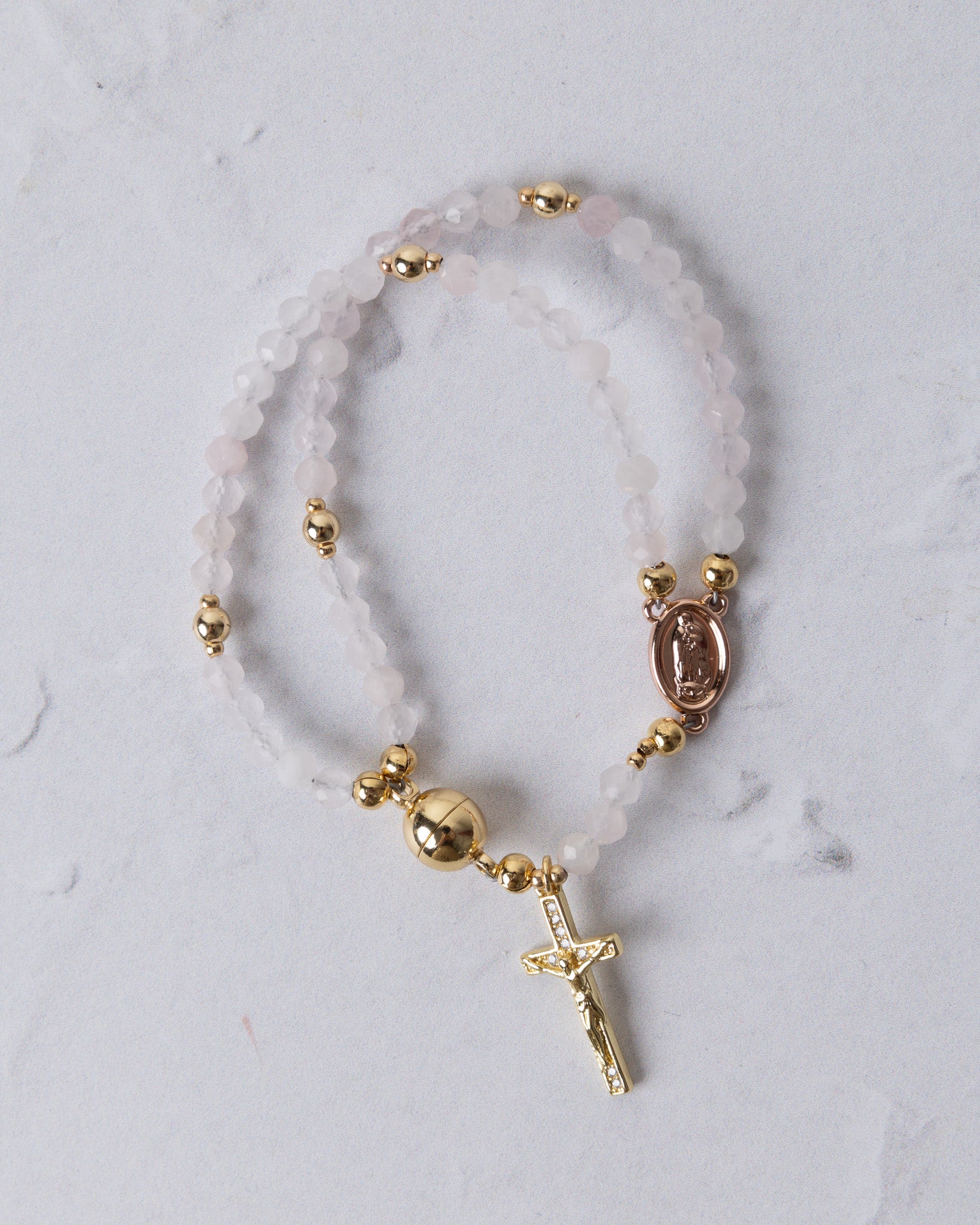 Rose quartz magnetic rosary bracelet with delicate double strands, translucent pink beads, gold-toned accents, and oval medallion