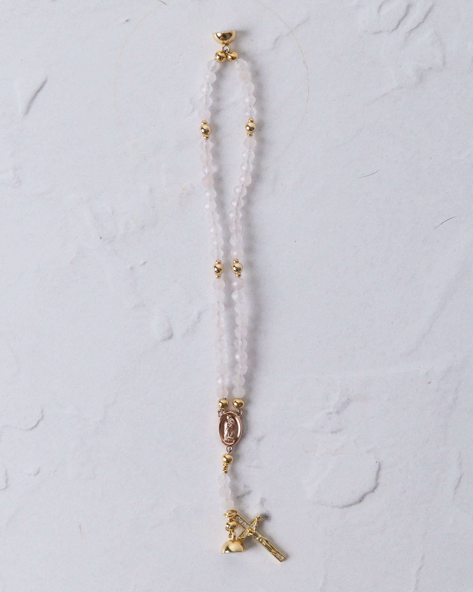 Rose quartz magnetic rosary bracelet with delicate white beads gold toned accents and golden cross pendant