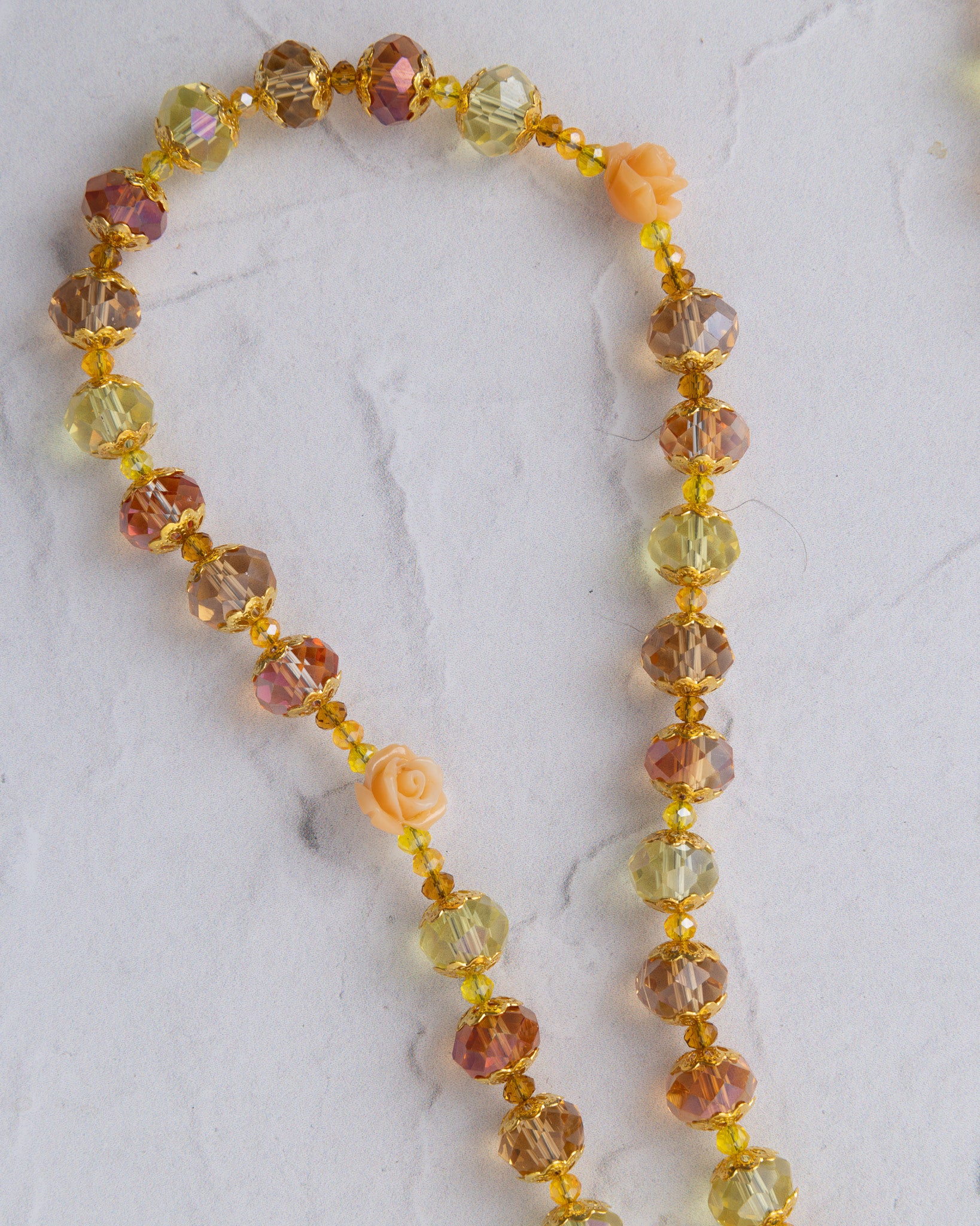 Metamorphosis rosary necklace with faceted amber peach yellow beads and small carved coral rose charms