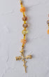 Metamorphosis rosary with delicate gold-toned chain, peach rose beads, amber crystals, and leafy cross pendant with gemstone