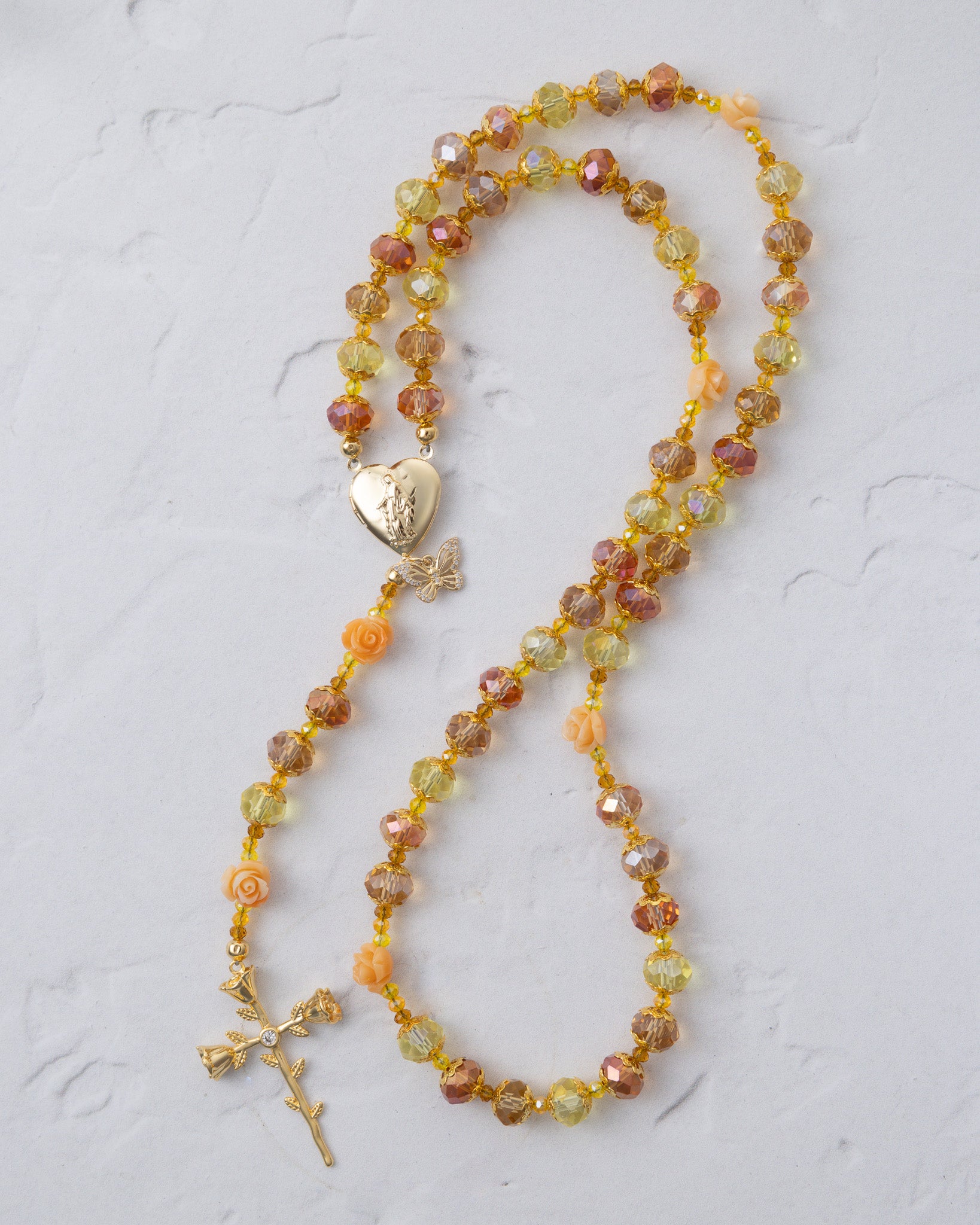 A delicate metamorphosis rosary with faceted amber yellow peach beads and gold heart locket with butterfly charm
