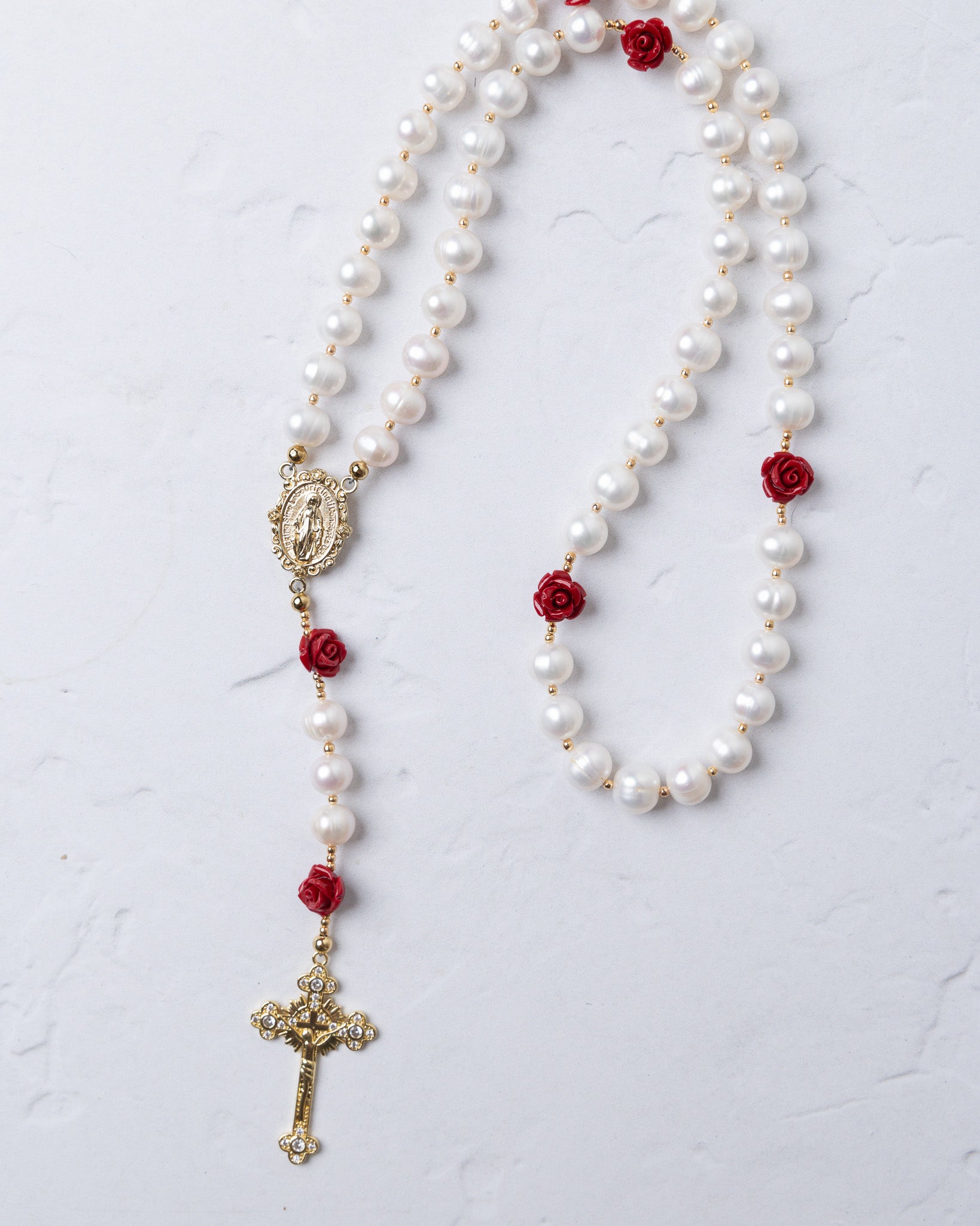 Ivory Rose Pearl Rosary featuring white pearls with red rose accents and gold-toned crucifix and medallion details