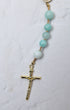 A delicate hydrangea rosary with light blue jade beads and a gold toned crucifix for prayer and devotion