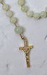 A lily of the valley rosary with delicate jade green beads and a gold toned crucifix with embedded crystals