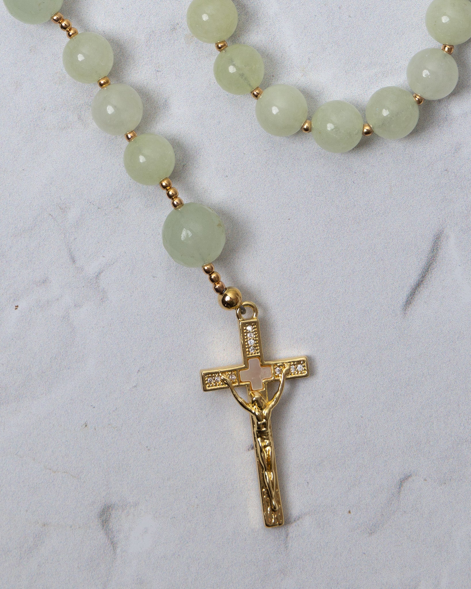 A lily of the valley rosary with delicate jade green beads and a gold toned crucifix with embedded crystals