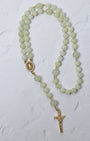 A delicate lily of the valley rosary with jade beads gold-toned metal accents and a detailed crucifix