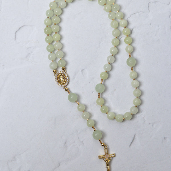 A delicate lily of the valley rosary with jade beads gold-toned metal accents and a detailed crucifix