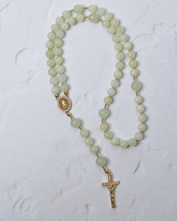 A delicate lily of the valley rosary with jade beads gold-toned metal accents and a detailed crucifix