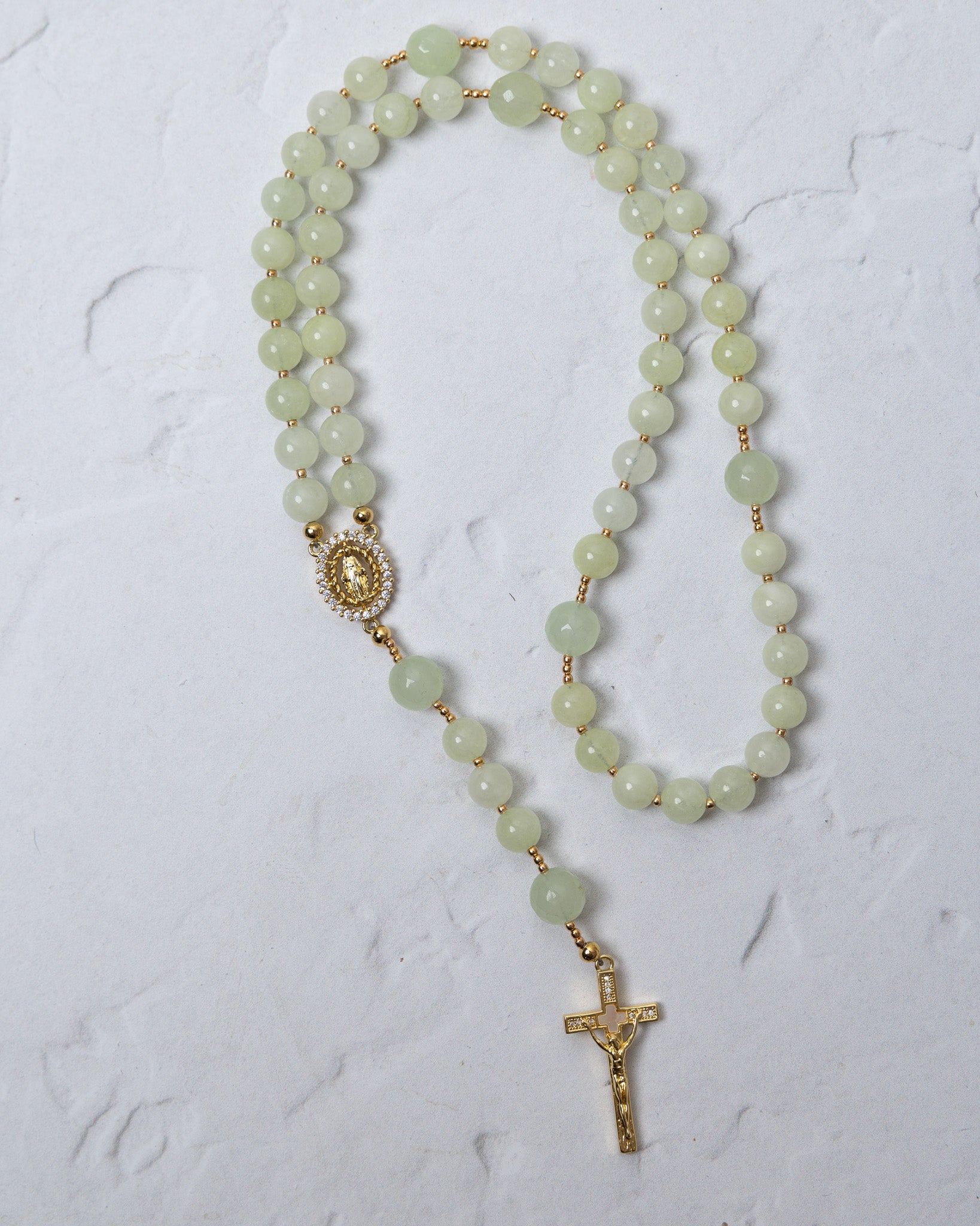 A delicate lily of the valley rosary with jade beads gold-toned metal accents and a detailed crucifix