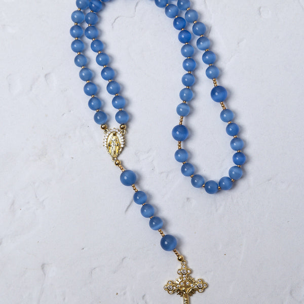 Bluebell rosary featuring delicate blue agate beads with gold-toned metal accents and a detailed cross pendant