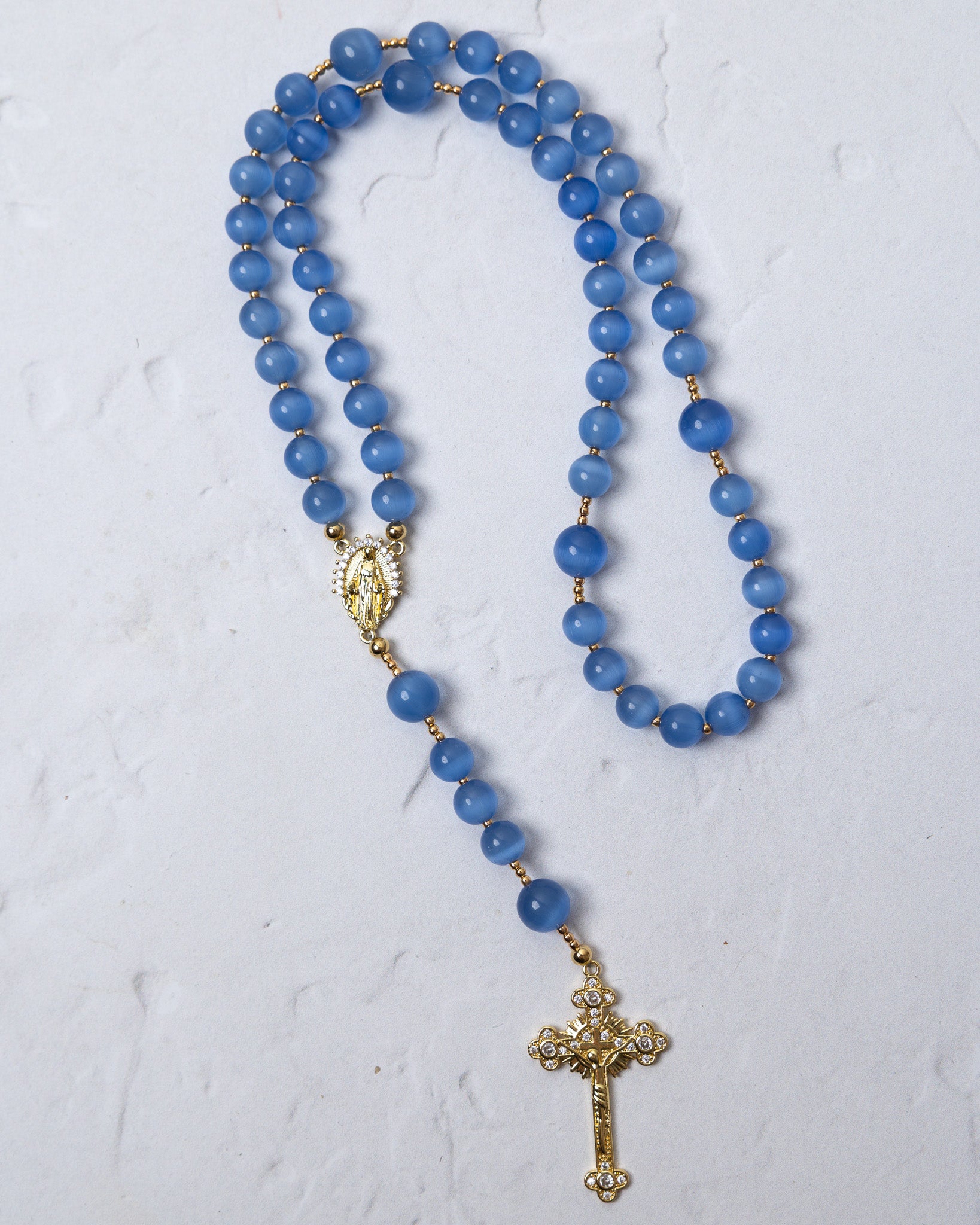 Bluebell rosary featuring delicate blue agate beads with gold-toned metal accents and a detailed cross pendant