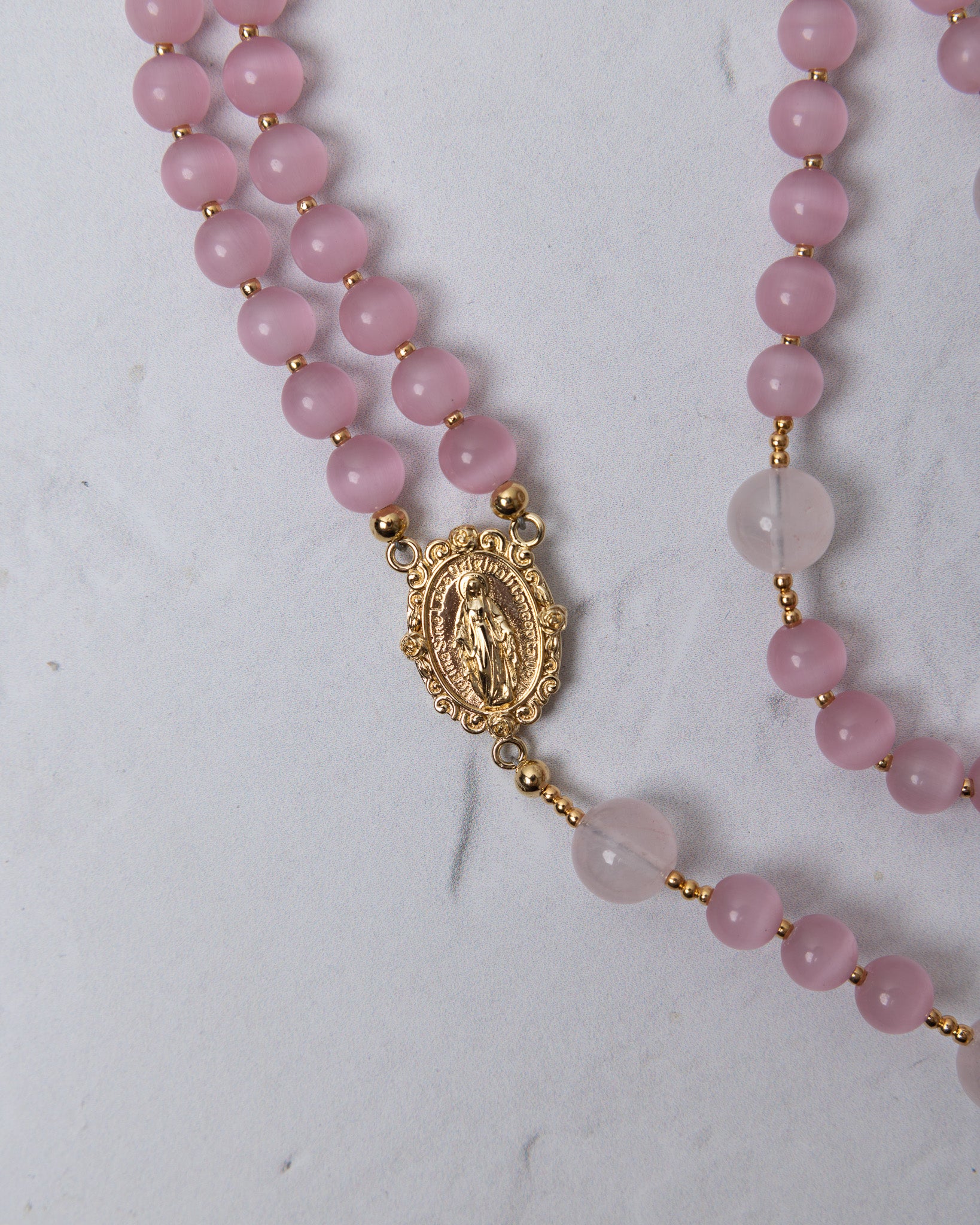 Sweet pea rosary featuring a delicate double-strand design with soft pink rose quartz beads and a gold-toned medallion