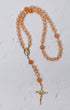 A peach-colored carnelian poppy rosary with gold-toned metal accents and a crucifix for prayer and meditation