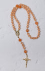 A peach-colored carnelian poppy rosary with gold-toned metal accents and a crucifix for prayer and meditation