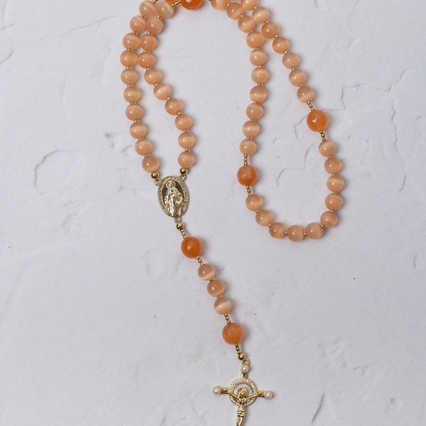 A peach-colored carnelian poppy rosary with gold-toned metal accents and a crucifix for prayer and meditation