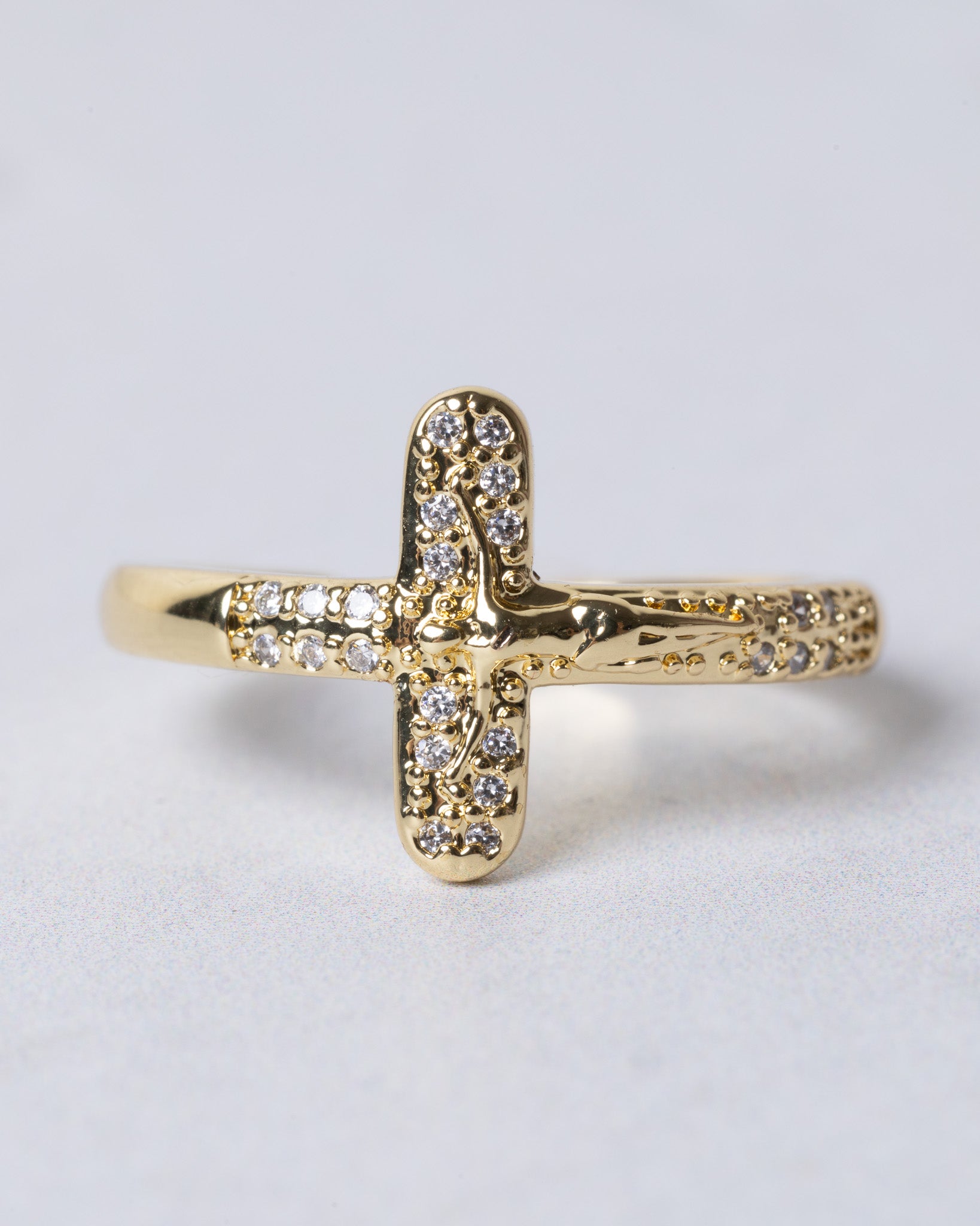 Gold crucifix ring adorned with sparkling clear stones along its arms and center for elegant wear