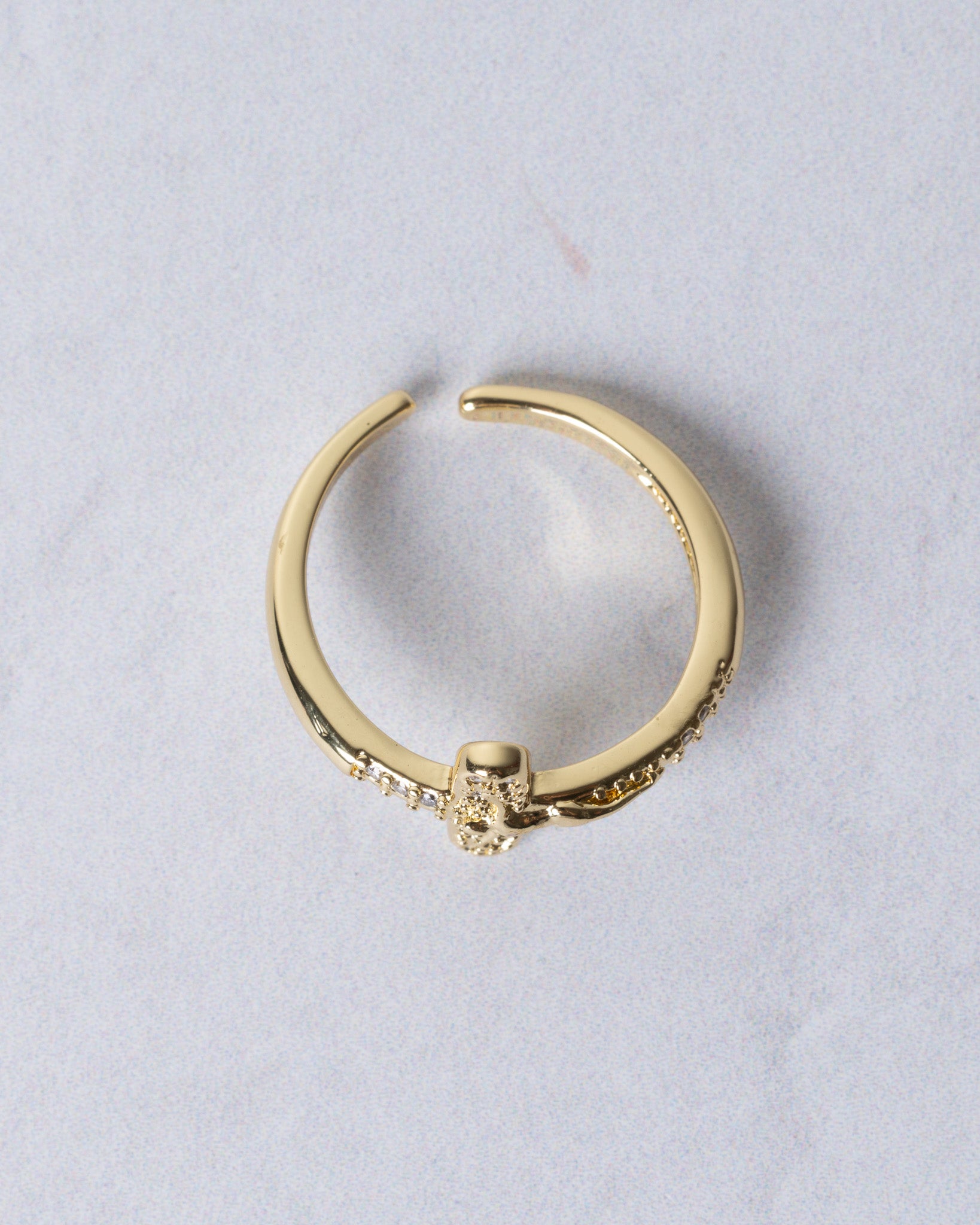 Gold-toned crucifix ring with adjustable band and delicate skull charm adorned with small clear stones