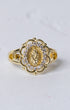 Gold-toned marian halo ring featuring an ornate floral design with a central religious figure and clear stones