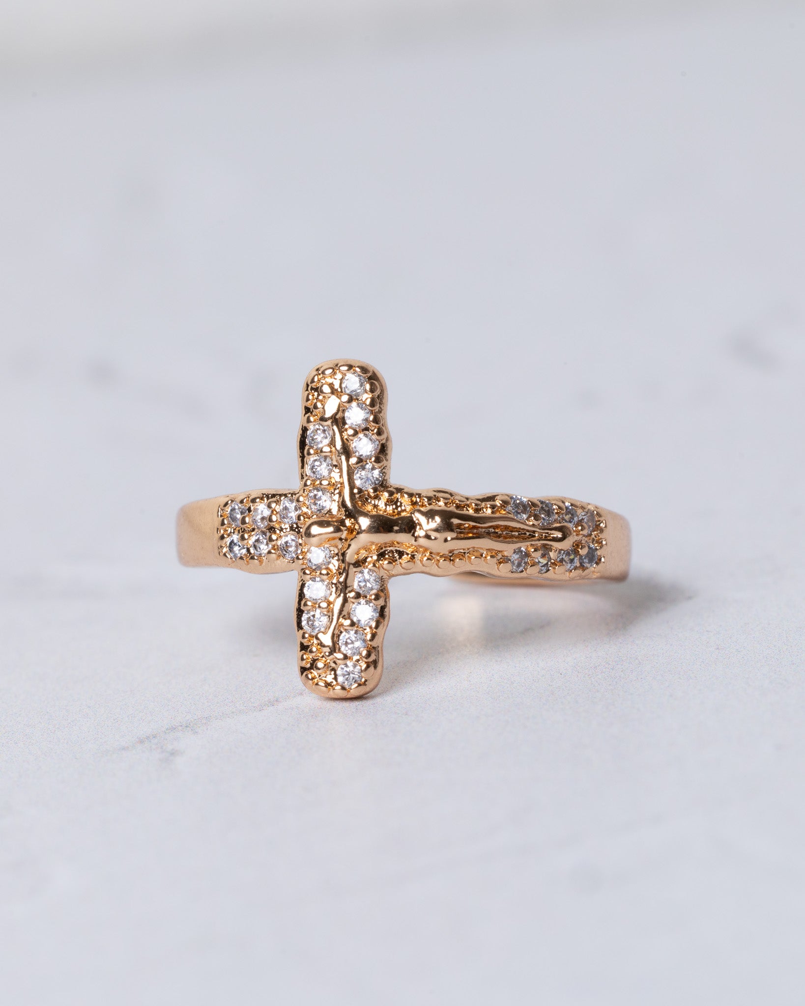 Gold-toned crucifix ring with clear sparkling stones along the cross arms and detailed figure at the center