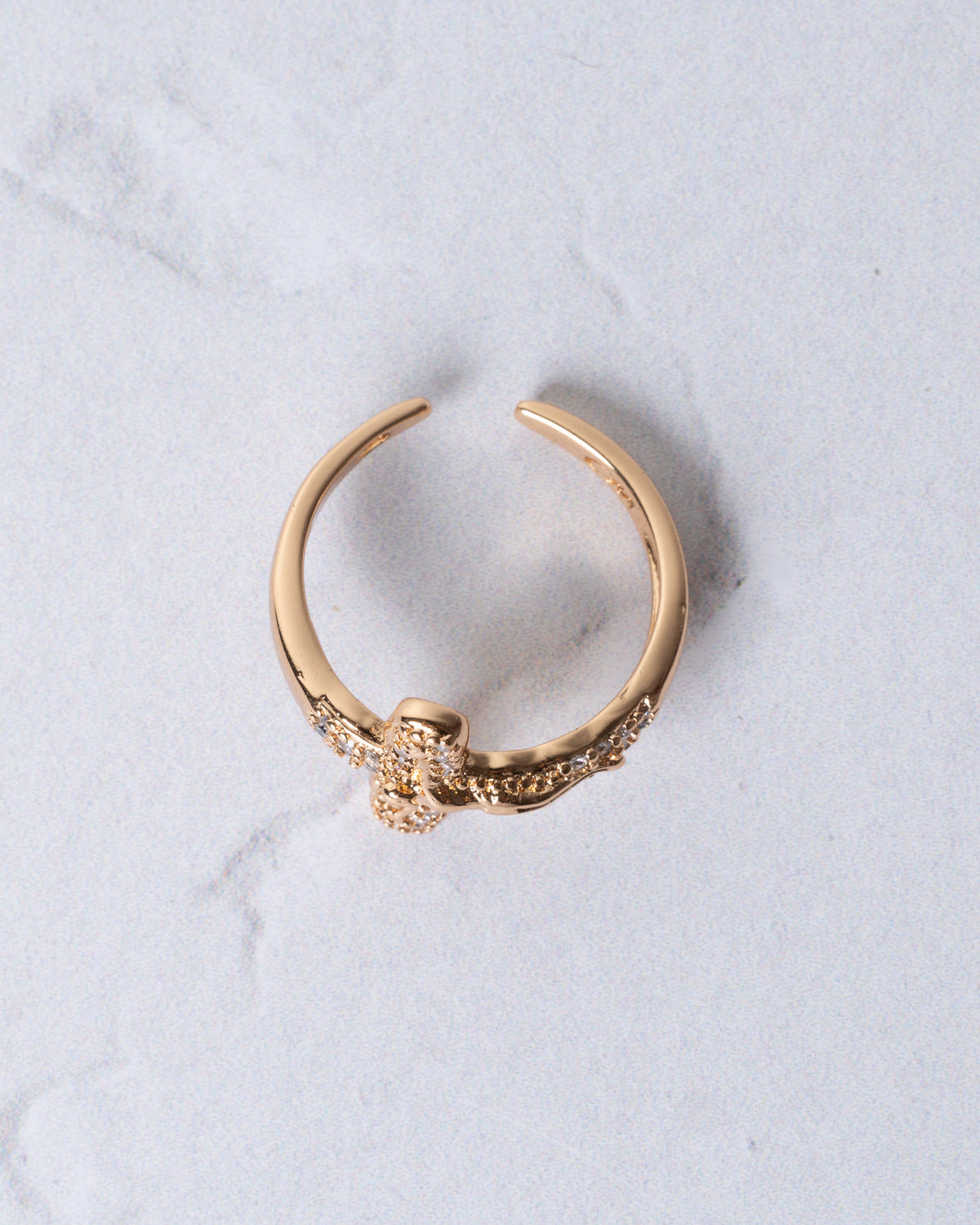 Gold-toned adjustable crucifix ring with central floral design adorned with sparkling clear stones