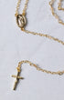 The Forever rosary necklace is a gold-toned chain with clear crystal accents and an oval medallion religious figure