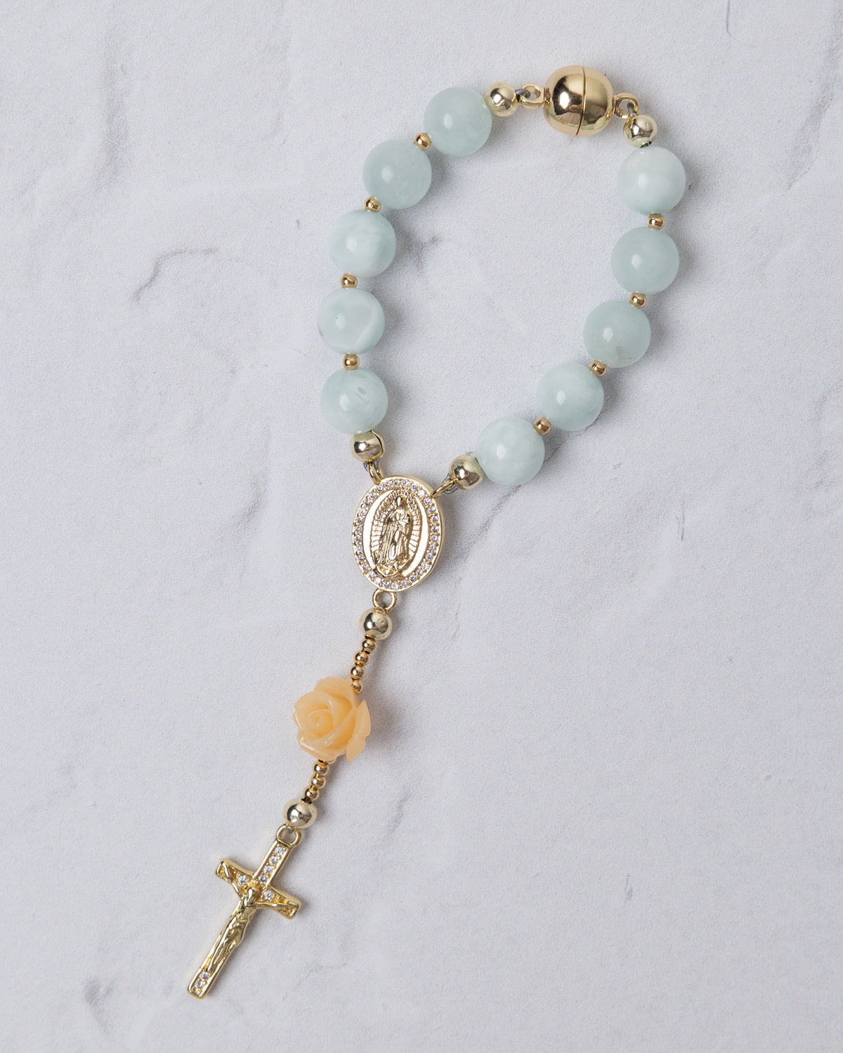 A delicate light blue jade bead bracelet with gold-toned accents and a peach rose charm in st thereses rose garden car rosary