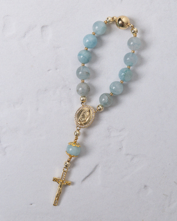 A delicate light blue jade car steering wheel rosary with gold toned metal accents and a small cross
