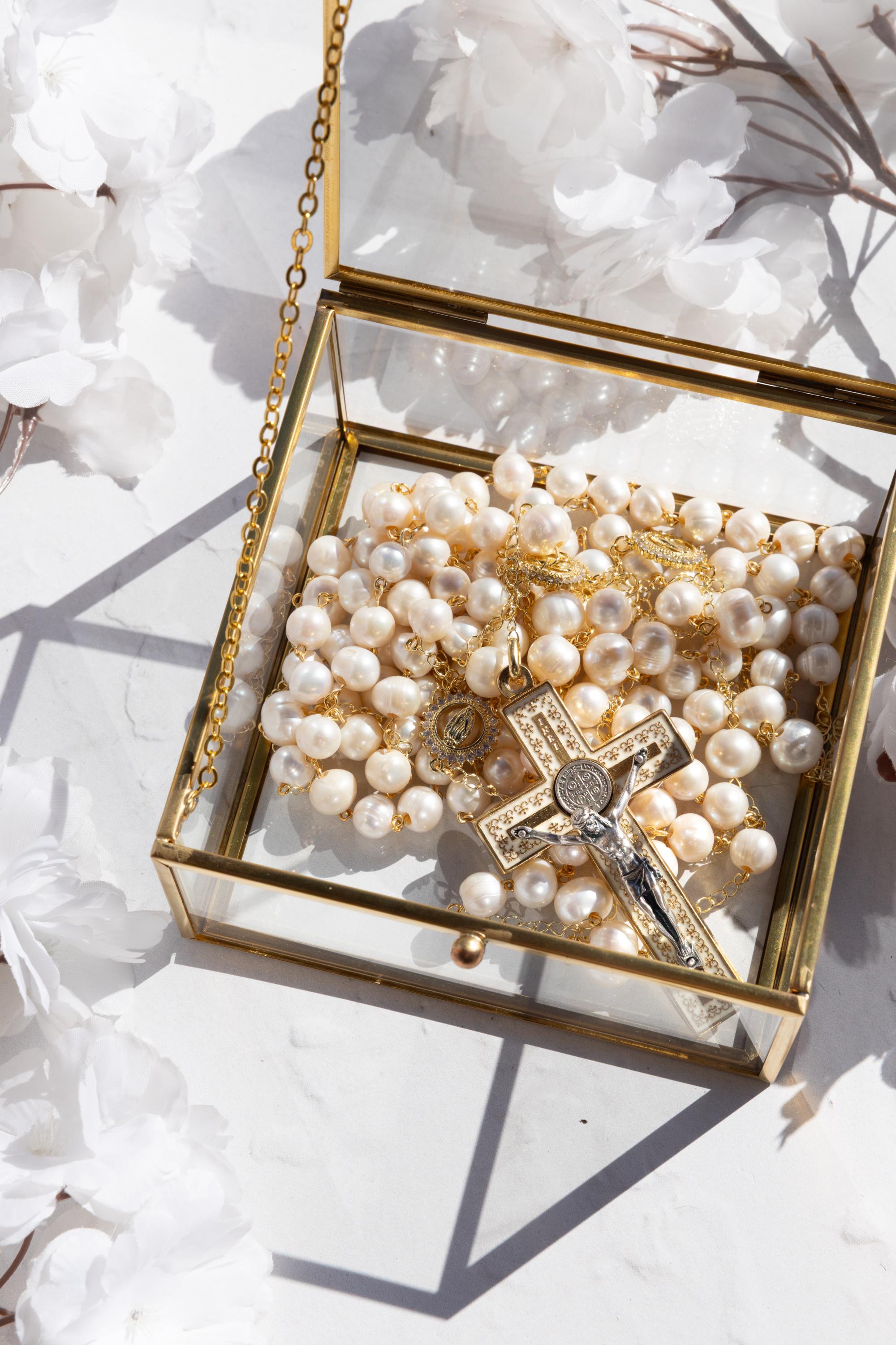 Freshwater pearl wedding lasso rosary displayed in a glass box with a gold cross and floral elements.