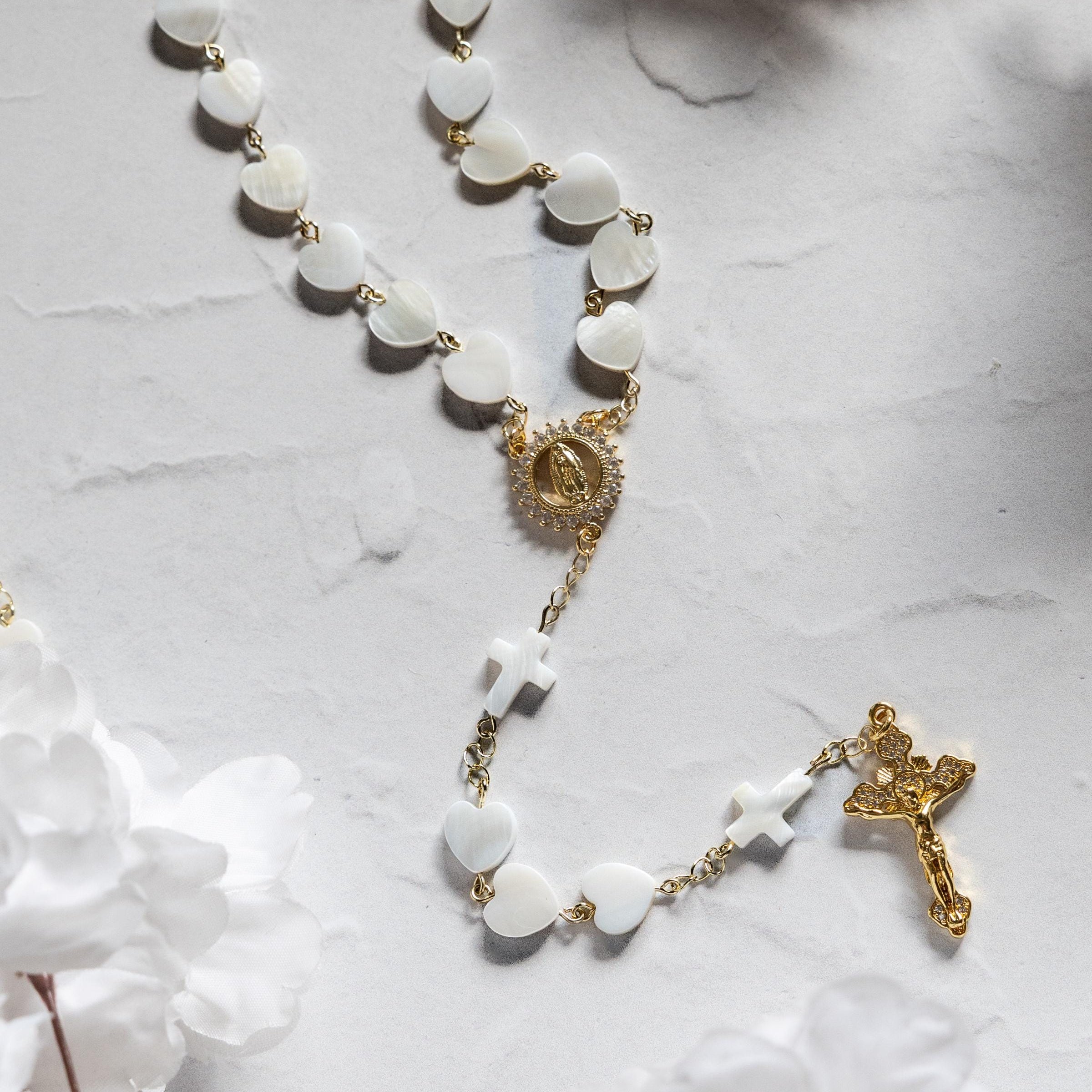 pearl heart shaped rosary with delicate gold accents and cross details on a light marble surface