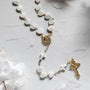 pearl heart shaped rosary with delicate gold accents and cross details on a light marble surface
