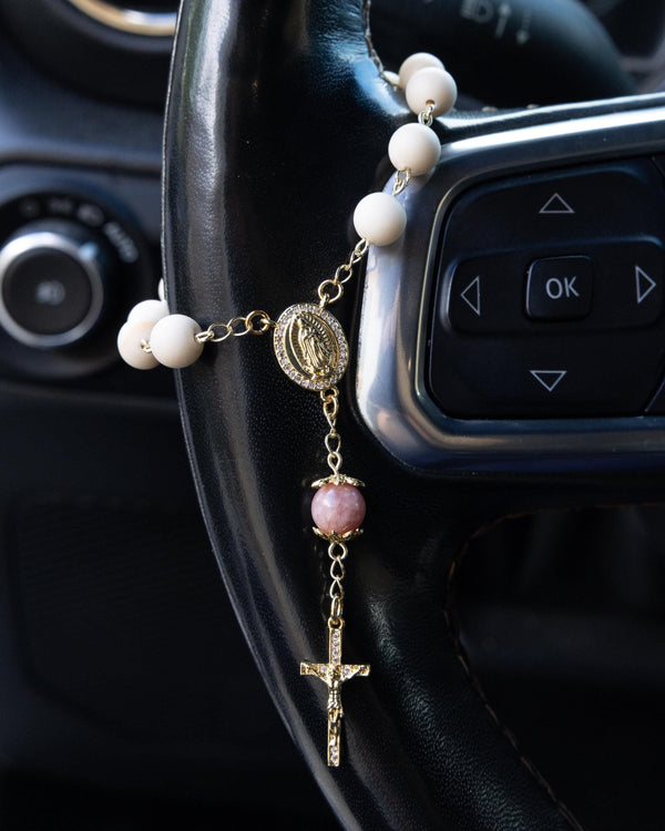 Delicate gold Soft Glory car decade rosary with cream beads on steering wheel