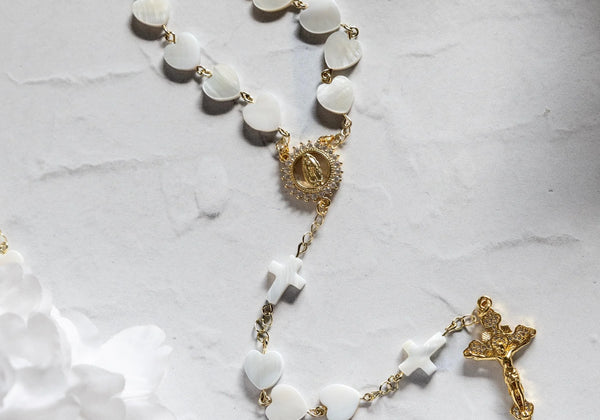 White heart-shaped shell rosary with gold-toned metal accents and a detailed crucifix.