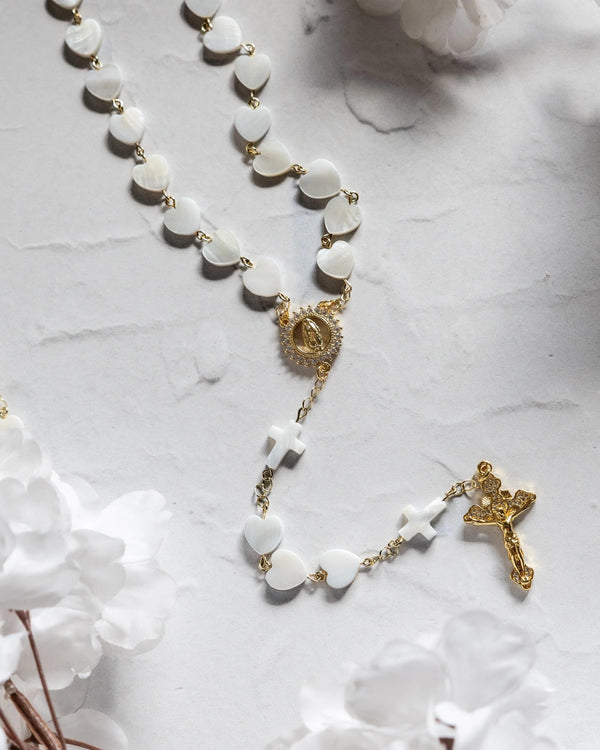 White heart-shaped shell rosary with gold-toned metal accents and a detailed crucifix.